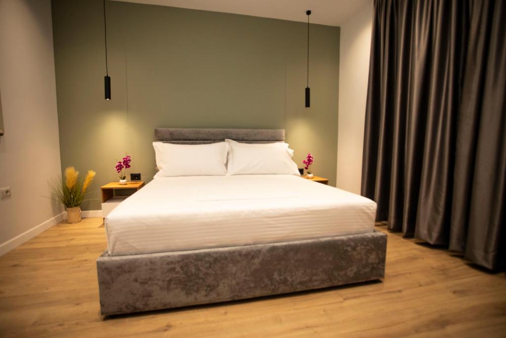 a bedroom with a large bed with white sheets at Villa Klaus Center Hotel in Tirana