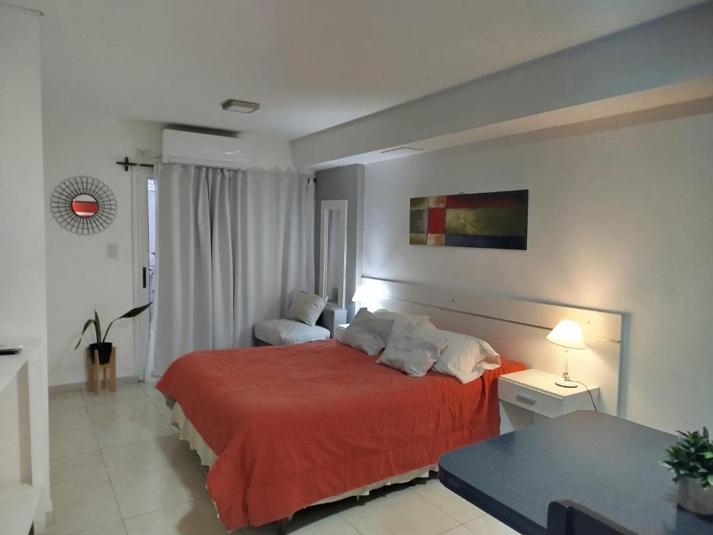 Hermoso departamento céntrico! في سان ميغيل دي توكومان: غرفة نوم بها سرير وبطانية حمراء