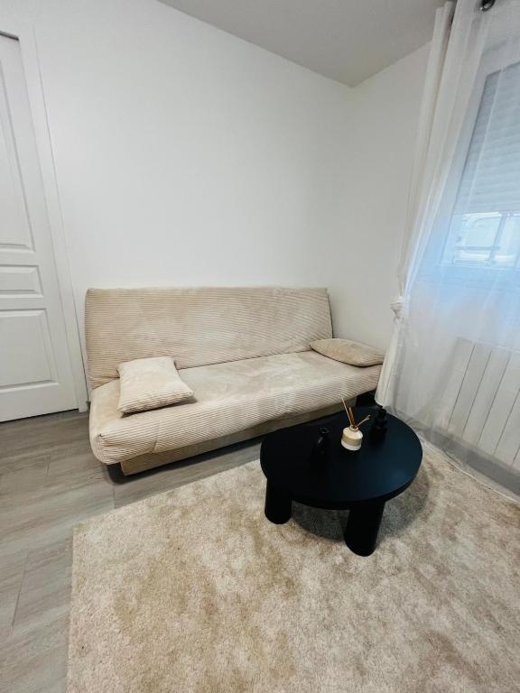 a living room with a couch and a table at Appartement cosy prêt de Paris Cdg, Astérix , Parc des expositions et Centre de formation CAMAS in Tremblay-En-France