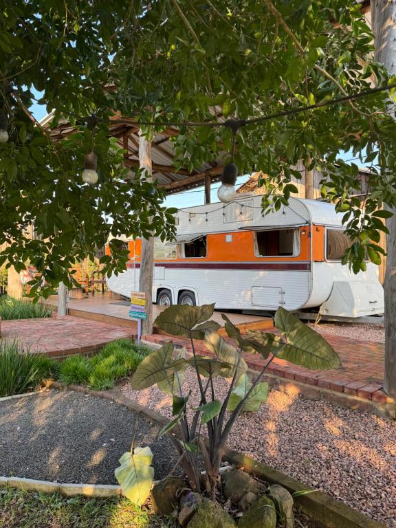 an orange and white rv parked under a building at Trailer Vintage no Sítio Wanderlust in Rolante