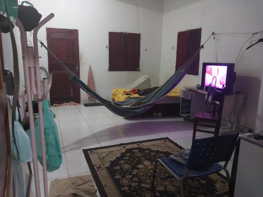 a room with a hammock and a tv in a room at Casa rua 09 de janeiro 13 in Benevides