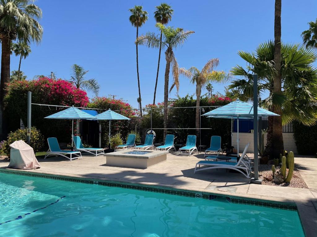 a swimming pool with blue chairs and umbrellas at Desert Paradise - A Men's Clothing Optional Resort in Palm Springs