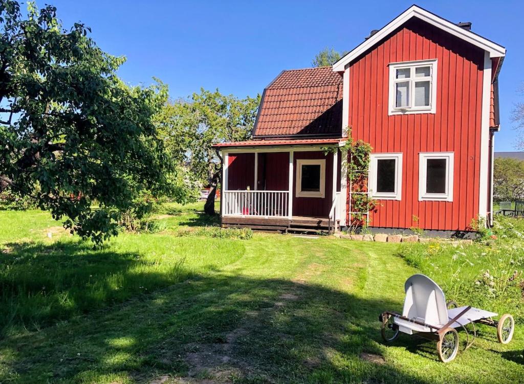 a red house with a wheelbarrow in front of it at Ferienhaus in Borghamn, Vättern in Borghamn