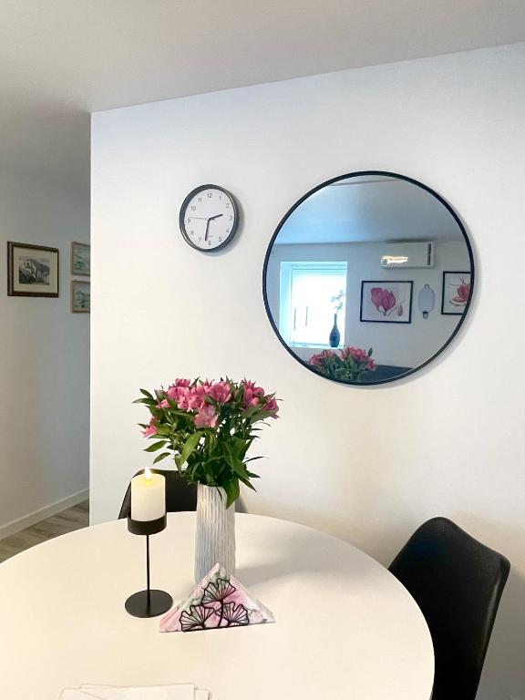 a round mirror above a table with a vase of flowers at Charming Modern Apartment Close to Moa & Ålesund in Ålesund