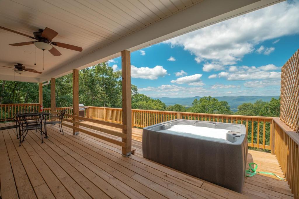 a hot tub on a deck with a view of the mountains at Sunset Cabin Privacy, Views, HotTub, Firepit, BBQ, Pets in Rileyville