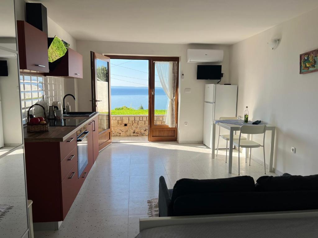 a kitchen and living room with a table and a refrigerator at Studio Apartment Ravel in Ičići