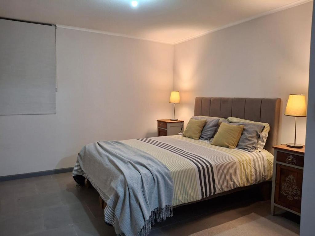 a bedroom with a bed with two night stands and two lamps at Departamento a Pasos de la UCM e Inacap in Talca