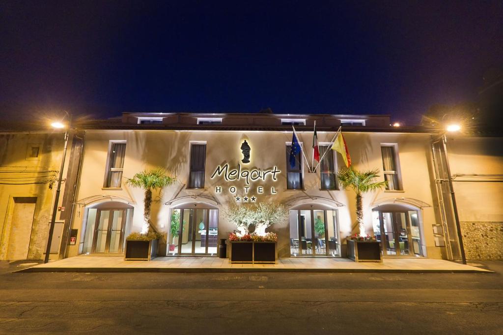 un hotel con un cartel en la parte delantera de la noche en Melqart Hotel, en Sciacca