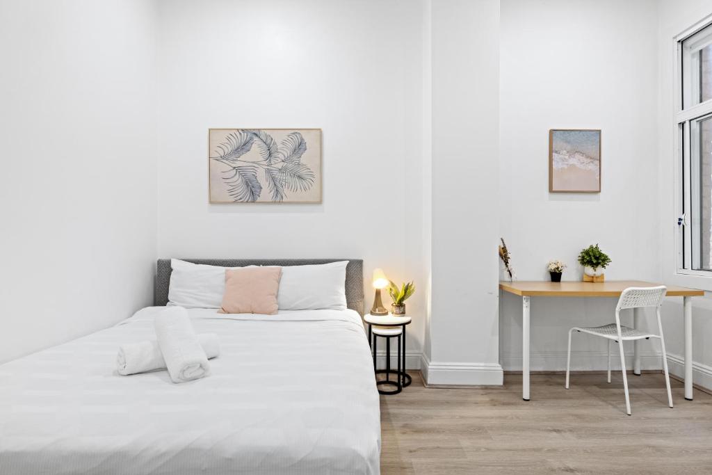a white bedroom with a bed and a desk at Cozy Double Room in Kensington - Walk to UNSW Easy CBD Access -External and Shared Kitchen or Bathroom Access in Sydney