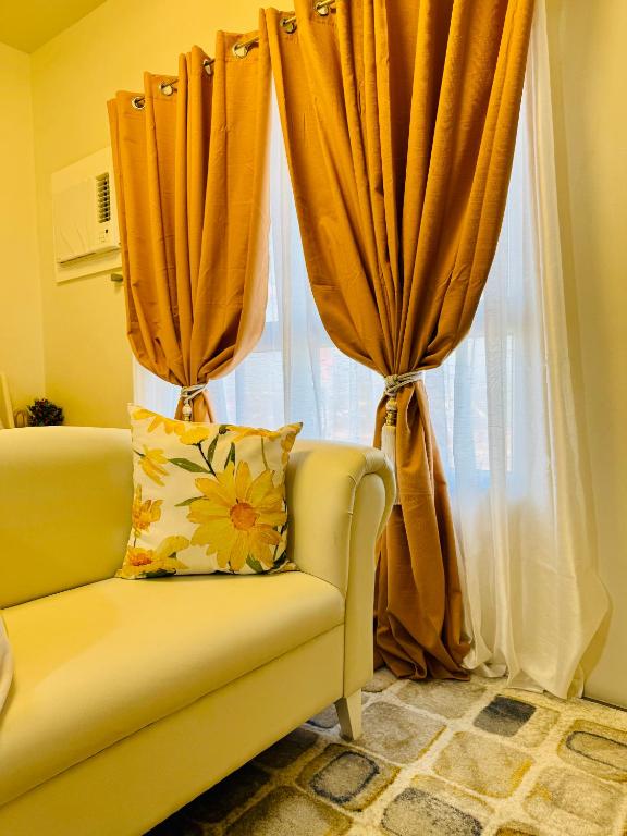 a yellow couch in front of a window with curtains at Mesavirre Garden Residences - Skybox Living in Bacolod