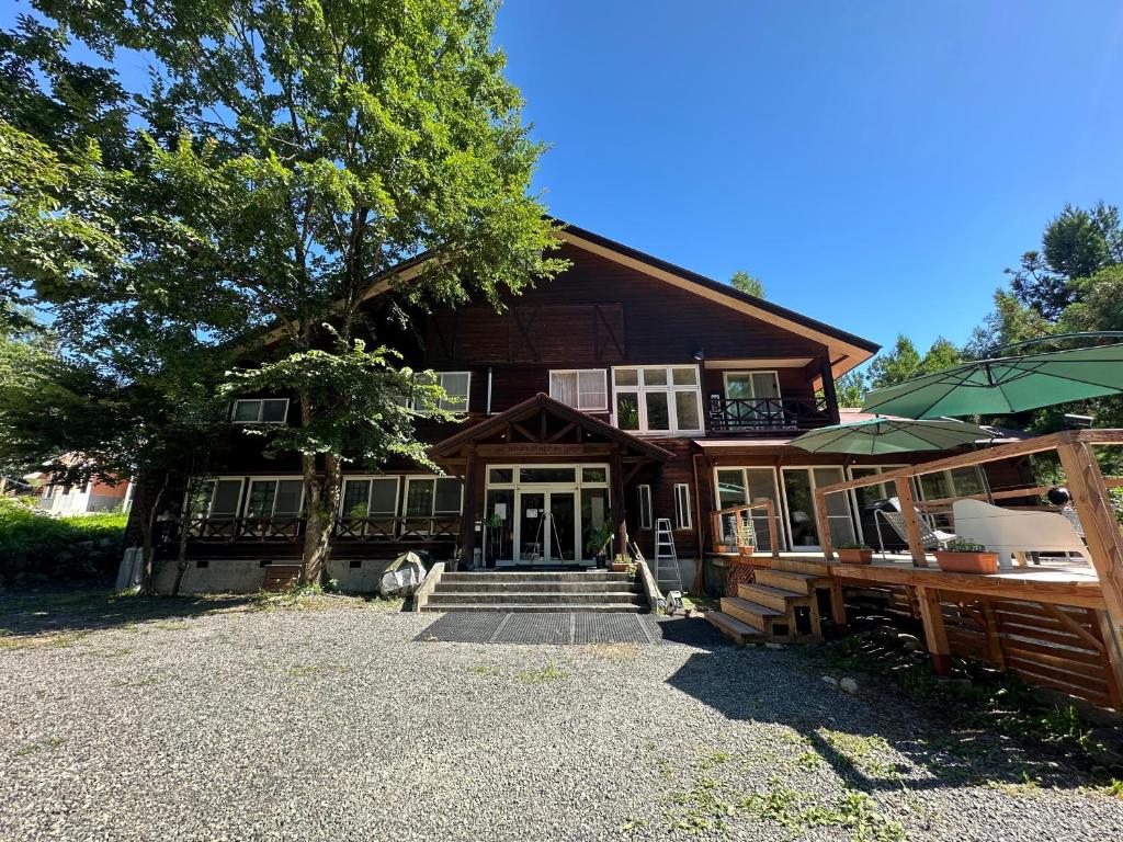 a large wooden house with a tree in front of it at Hakuba Third Place Lodge in Hakuba