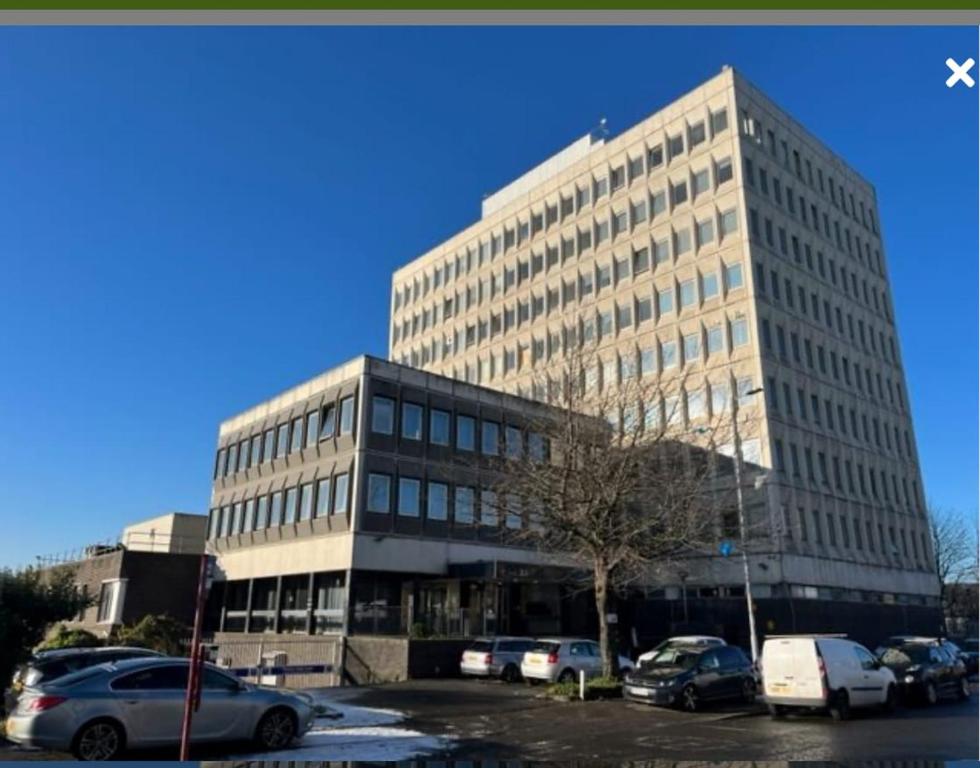 a large building with cars parked in a parking lot at City Views Top Floor - Bradford City Center in Bradford