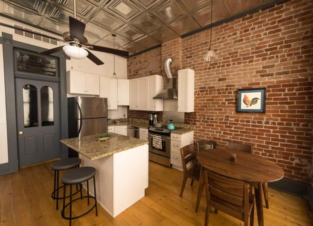 a kitchen with a brick wall and a table at Sunny Downtown Condo Above The Coffee Shop in Salida