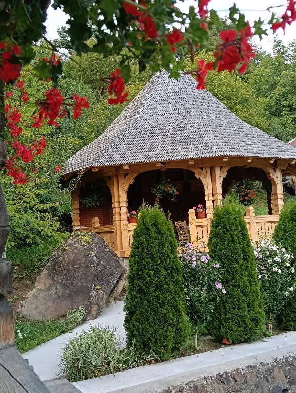 a small wooden gazebo in a garden with flowers at Casa Boris in Bîrsana