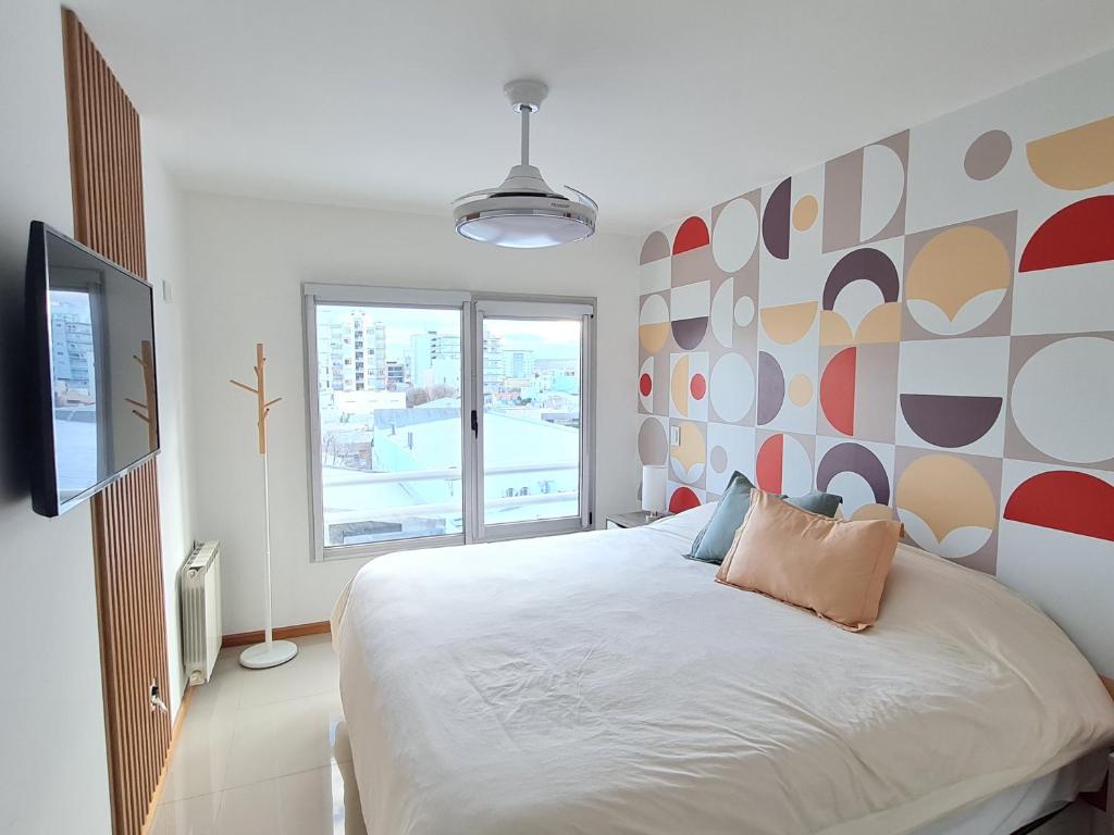 een slaapkamer met een bed en een groot raam bij AC Suites XL in Puerto Madryn