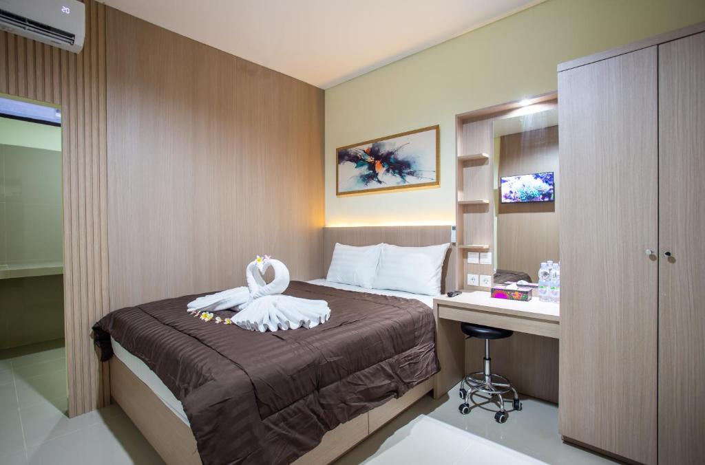 a hotel room with a bed and a desk at Opang Asri Guesthouse Sanur in Sanur