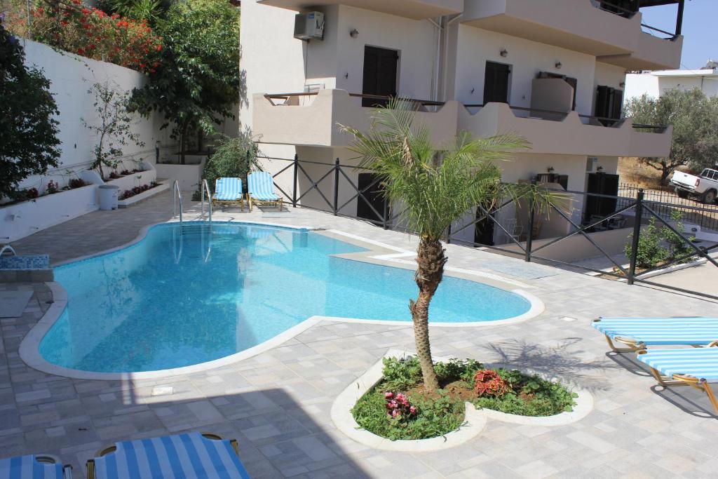 een zwembad met een palmboom voor een gebouw bij Istron Blue in Istron