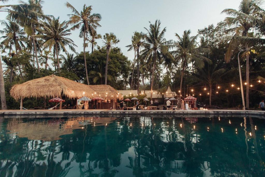 una piscina en un resort con palmeras en Barefoot Glamping - Escape in Nature, en Tianyar