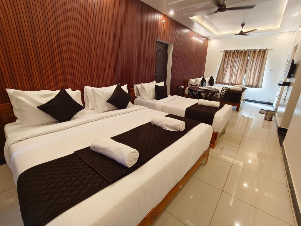 a hotel room with two beds and a desk at Sai RBM Grand Inn in Kuilapayam