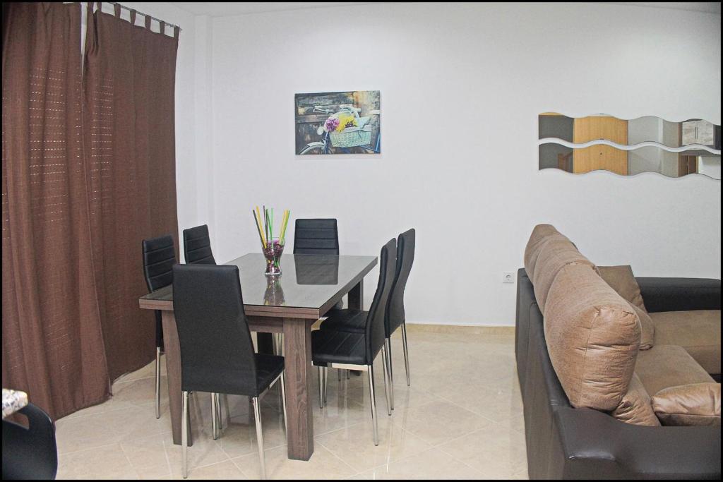 comedor con mesa, sillas y sofá en Apartamento Loyola, en Conil de la Frontera