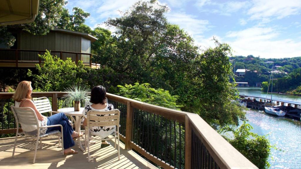 two women sitting at a table on a balcony overlooking a river at Lakefront Bungalow With Community Poolhot Tub #5 in Lakeway