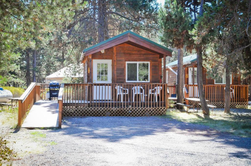 Cabaña de madera con puerta y sillas en un patio en Bend-Sunriver Camping Resort Studio Cabin 8, en Sunriver