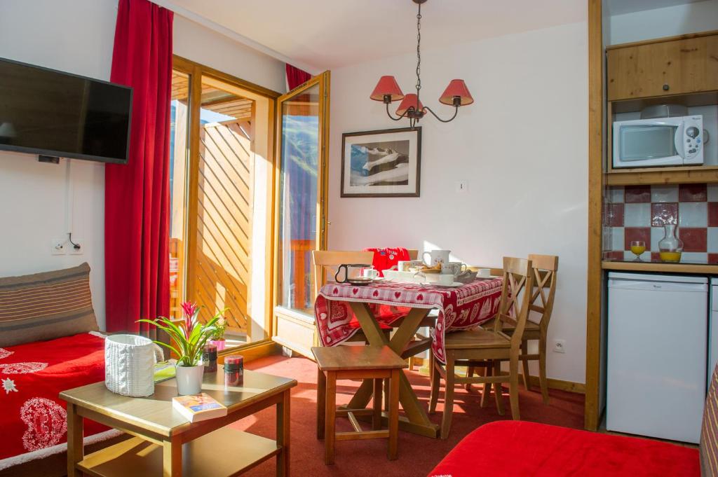 ein Wohnzimmer mit einem Tisch und Stühlen sowie eine Küche in der Unterkunft Résidence Goélia Les Chalets Valoria in Valloire