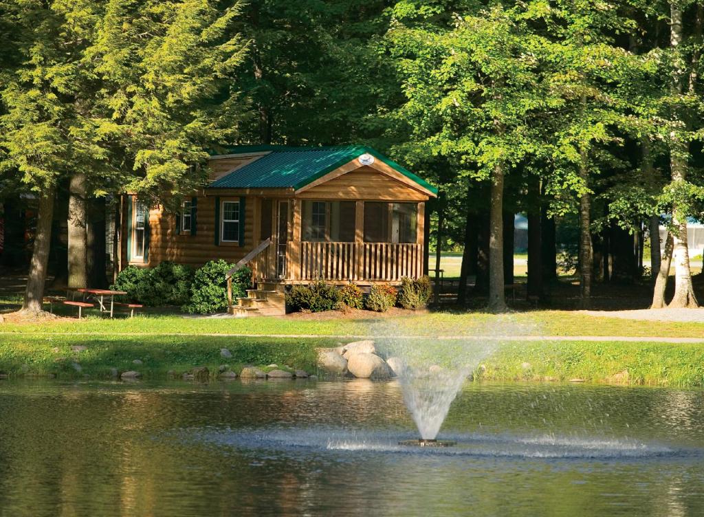 a fountain in the water in front of a log cabin at Alpine Lake Lakefront Cabin 5 in South Corinth