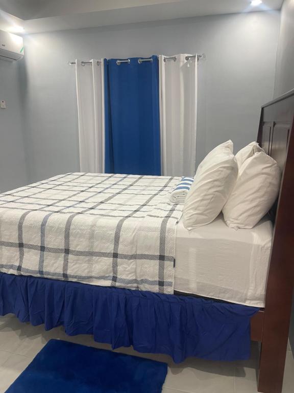 迪斯卡弗里贝Blue coral Villa Jamaica的卧室里有一张带蓝色窗帘的床