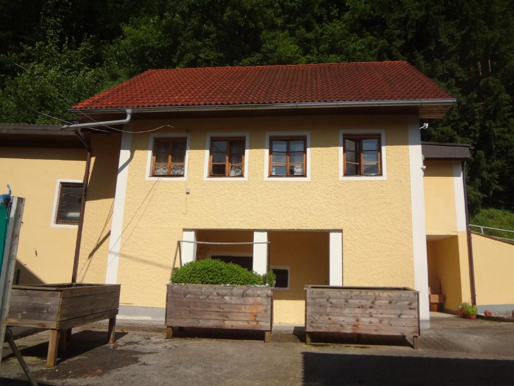 dom z dwoma oknami i dwoma drewnianymi pudłami z przodu w obiekcie Ferienhaus am Fluss w mieście Pinsdorf