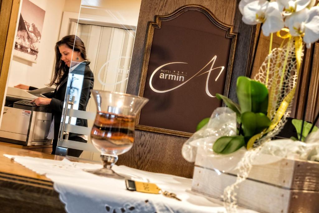 een vrouw die achter een tafel staat met een wijnglas bij Hotel Armin in Selva di Val Gardena