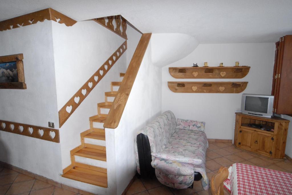 Pokój ze schodami, krzesłem i telewizorem w obiekcie La Coquille Apartment w mieście Breuil-Cervinia