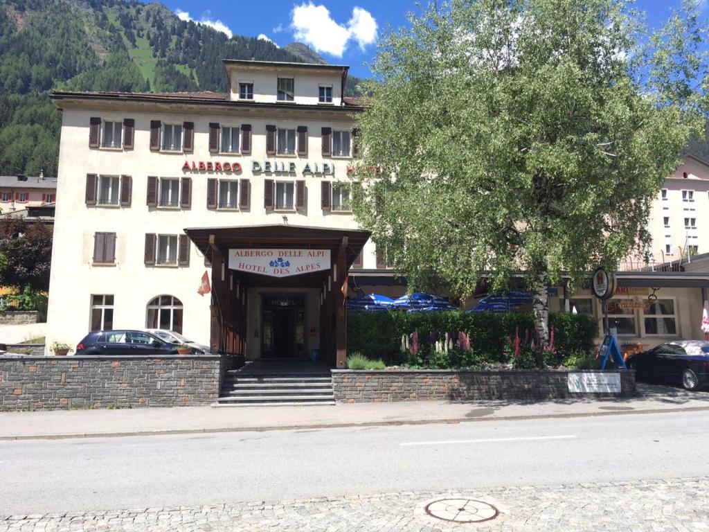 ein großes weißes Gebäude mit einem Schild davor in der Unterkunft Hotel Des Alpes - Restaurant & Pizzeria in Airolo