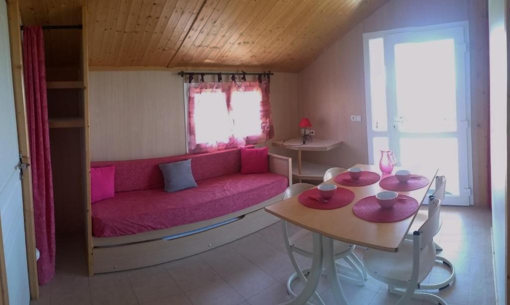 a living room with a pink couch and a table at Les Chalets du Piou in Bussières