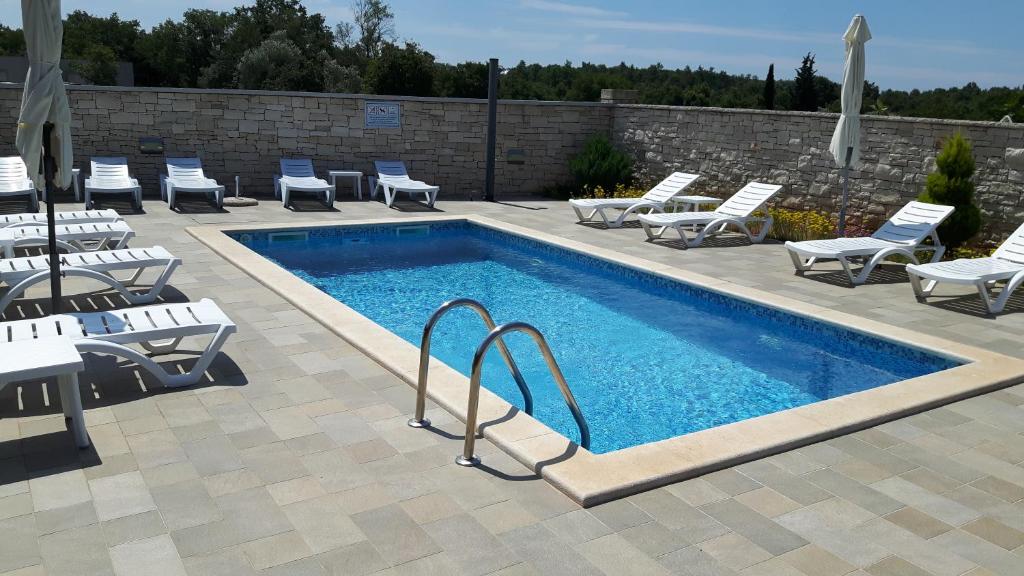 a swimming pool with chaise lounge chairs and a swimming pool at Apartments & Rooms Villa Adamović in Umag