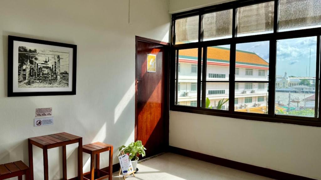 Una habitación con dos bancos y una ventana en un edificio. en Baan PadSeeEw - Rooftop Riverview 4th floor, en Thonhuri