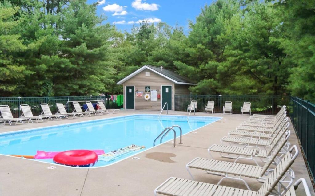 a swimming pool with lounge chairs and a red frisbee at Cedarwood Lodge Community Pool! in Saugatuck