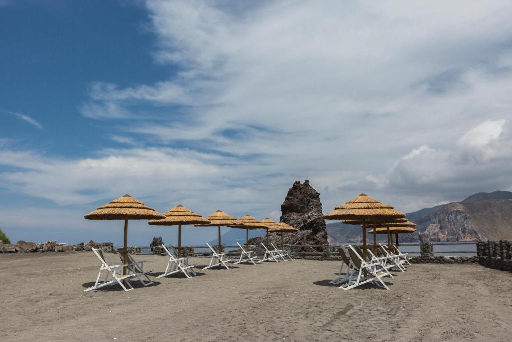 a group of chairs and umbrellas on a beach at Mari del Sud Resort in Vulcano
