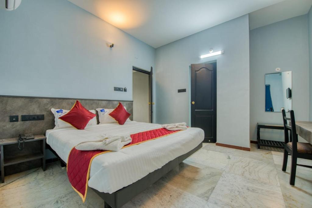 a bedroom with a large bed with red pillows at Corbelli Residency in Pondicherry