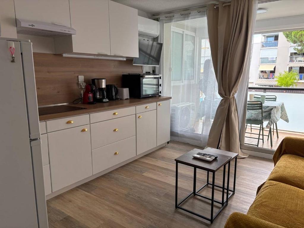 una cocina con armarios blancos y una mesa en una habitación en Ondine, en Gruissan