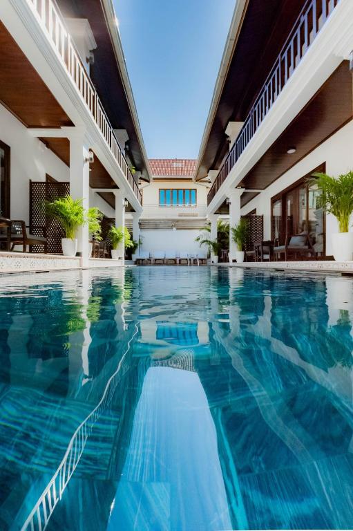 a swimming pool in a hotel with blue water at Cozy An Luangprabang Hotel in Luang Prabang