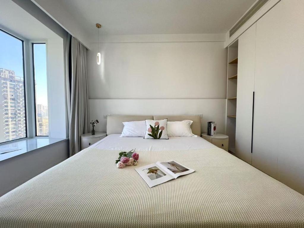 a bedroom with a bed with a book and flowers on it at Urban Hub Near the Bund nice view big apartment 2bathrooms in Shanghai