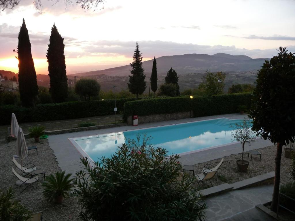 a swimming pool with a sunset in the background at Hotel Villa Dei Bosconi in Fiesole