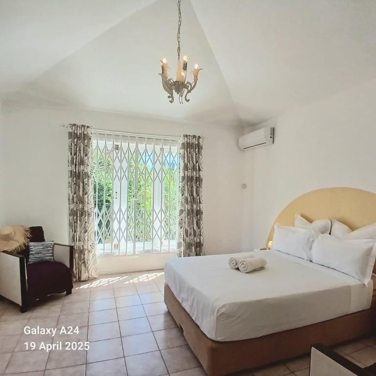 a bedroom with a bed and a window with a chandelier at The Coral House in Rivière Noire
