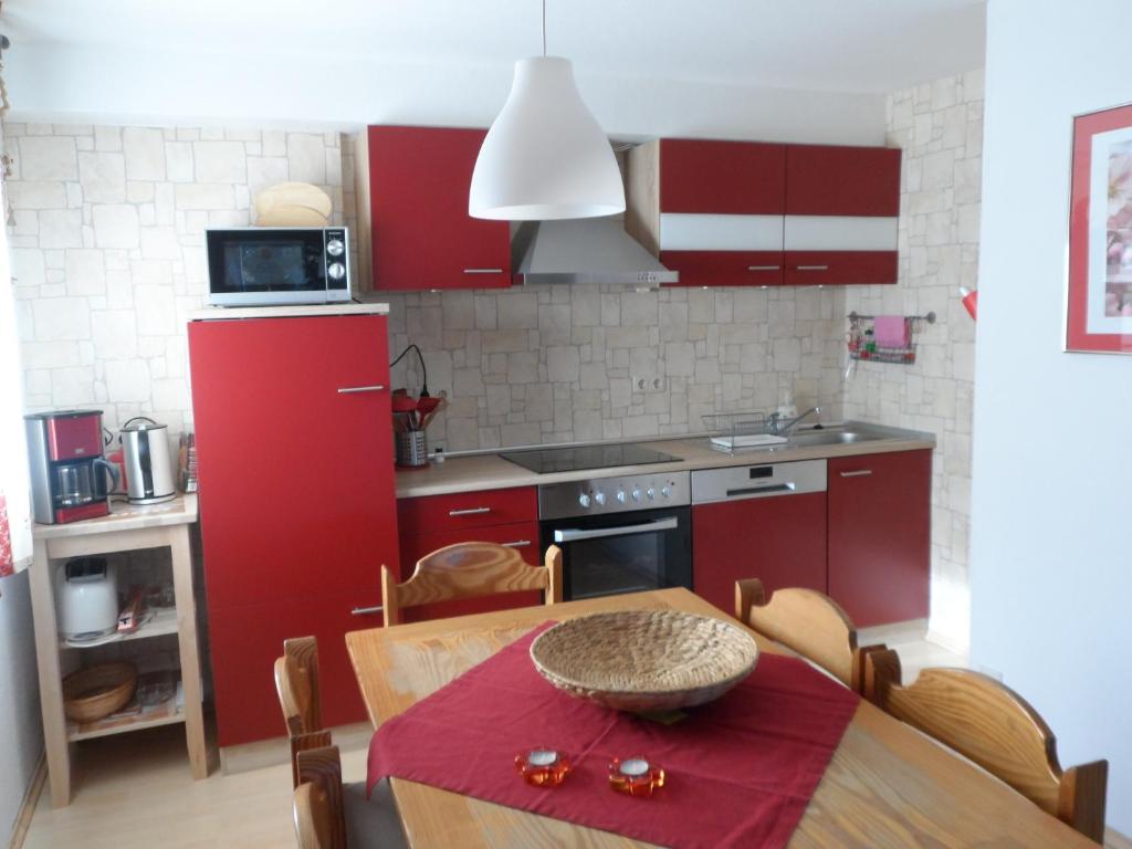 ブラウンラーゲにあるFerienwohnung Ortliebの赤いキャビネットとテーブル(赤いテーブルクロス付)が備わるキッチン