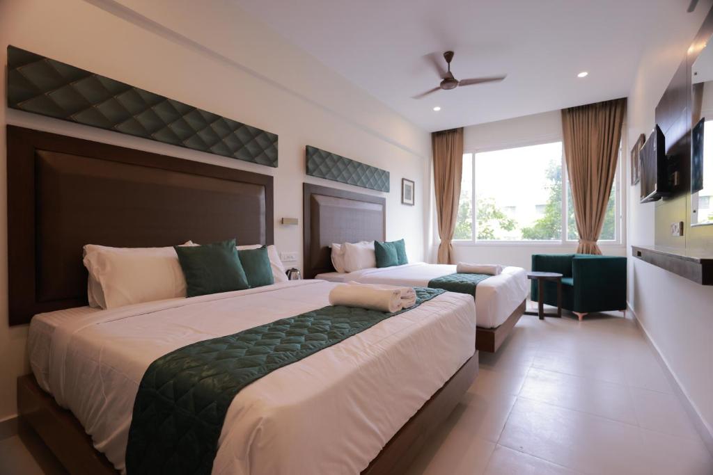 a hotel room with two beds and a window at Hotel Aavudai Grand in Aramboly