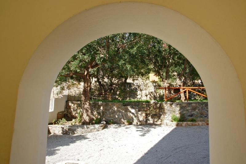 an archway with a stone wall and a tree at Aretousa in Sougia