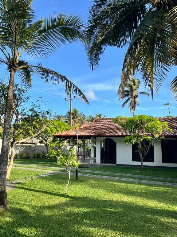 a house with palm trees in front of a yard at Dona's Villa, Coastal Tropical House in Kepungoda
