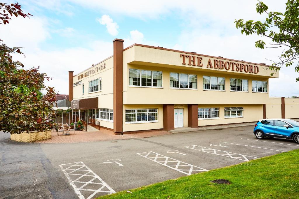 een gebouw met een auto geparkeerd op een parkeerplaats bij Abbotsford Hotel in Dumbarton