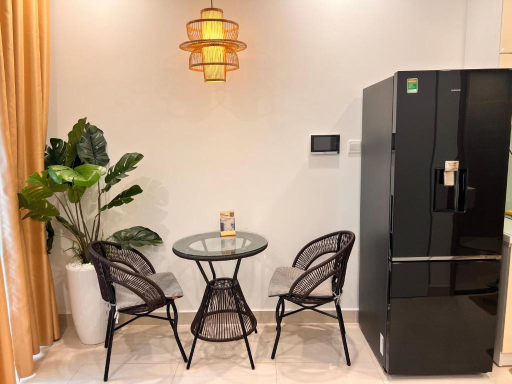 a table and chairs with a small table and a black refrigerator at Vinhome Grand Park Homestay-ZEN Garden House in Long Bình